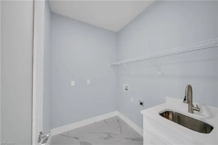 Laundry area featuring baseboards, electric dryer hookup, laundry area, hookup for a washing machine, and a sink