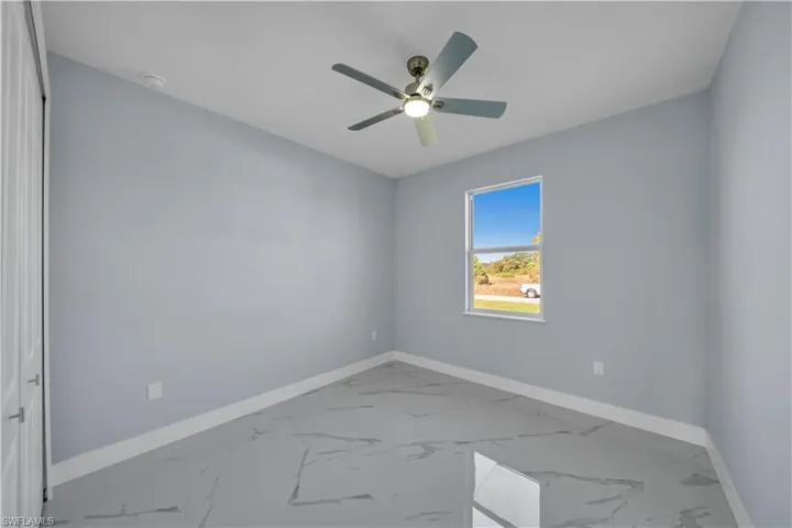 Unfurnished room featuring marble finish floor, baseboards, and ceiling fan