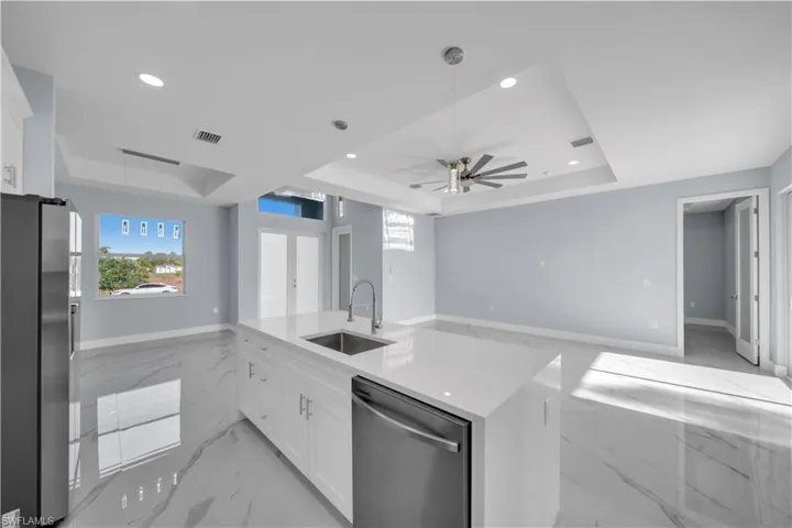 Kitchen featuring stainless steel appliances, a sink, a ceiling fan, and a raised ceiling