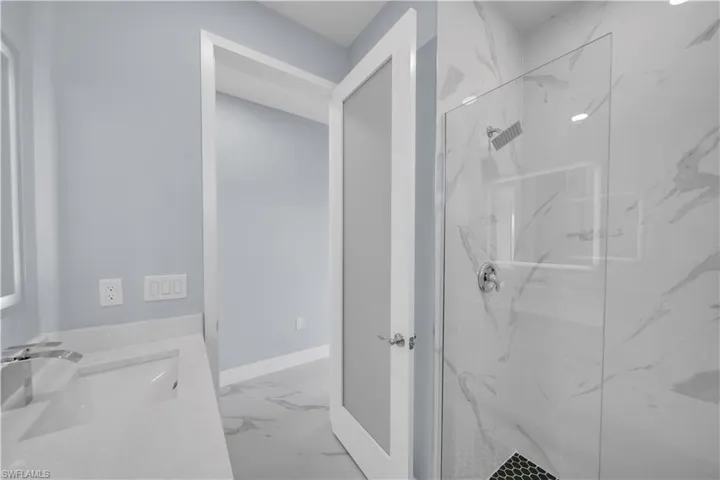 Full bathroom featuring a marble finish shower, marble finish floor, and vanity