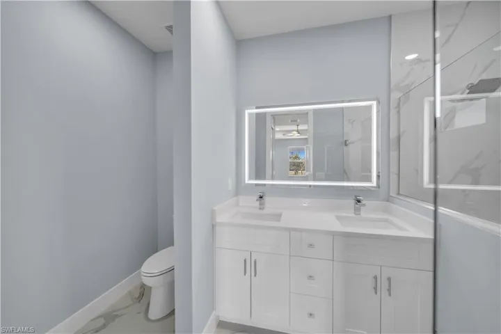 Bathroom with double vanity, marble finish floor, a sink, and toilet