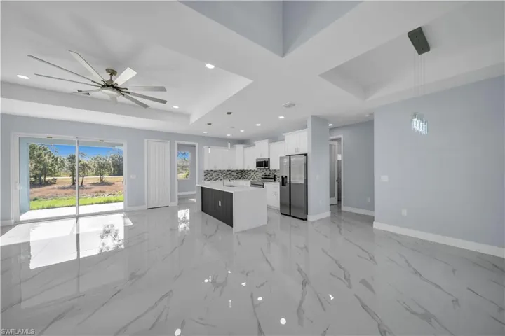 Kitchen with a kitchen island, appliances with stainless steel finishes, light countertops, a raised ceiling, and baseboards