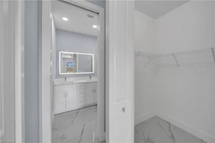 Walk in closet with visible vents, marble finish floor, and a sink