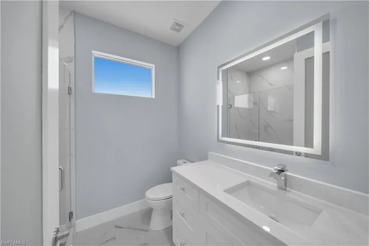 Bathroom with visible vents, toilet, vanity, a marble finish shower, and marble finish floor