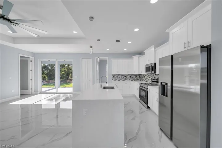 Kitchen with a sink, appliances with stainless steel finishes, marble finish floor, and recessed lighting