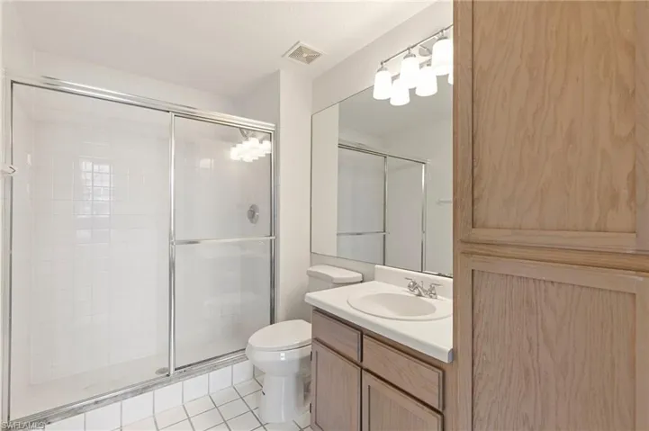 Bathroom in main bedroom with tiled shower, tile patterned floors, and vanity