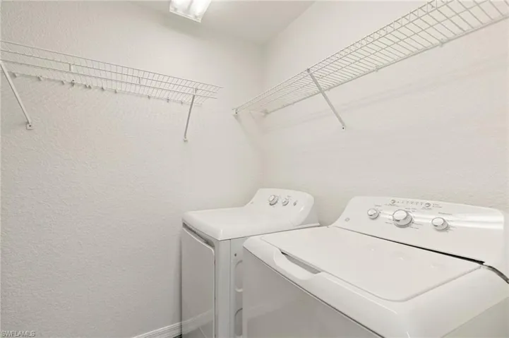 Laundry area featuring washer and dryer and a textured wall