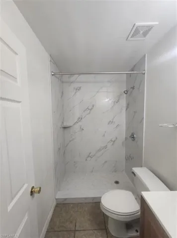 Bathroom with vanity, a marble finish shower, and light tile patterned floors