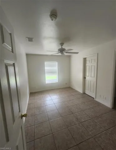 Unfurnished bedroom featuring ceiling fan and dark tile patterned flooring