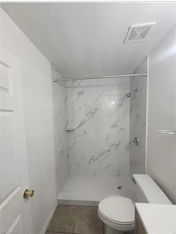Full bathroom with vanity, a marble finish shower, and tile patterned flooring