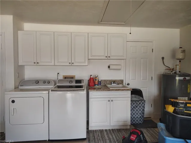 Laundry room with separate washer and dryer, a sink, water heater, cabinet space, and attic access