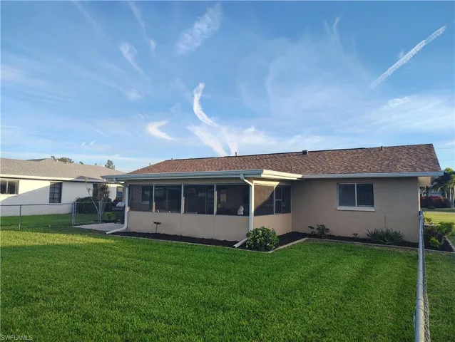 Back of house with a sunroom, stucco siding, a lawn, and fence