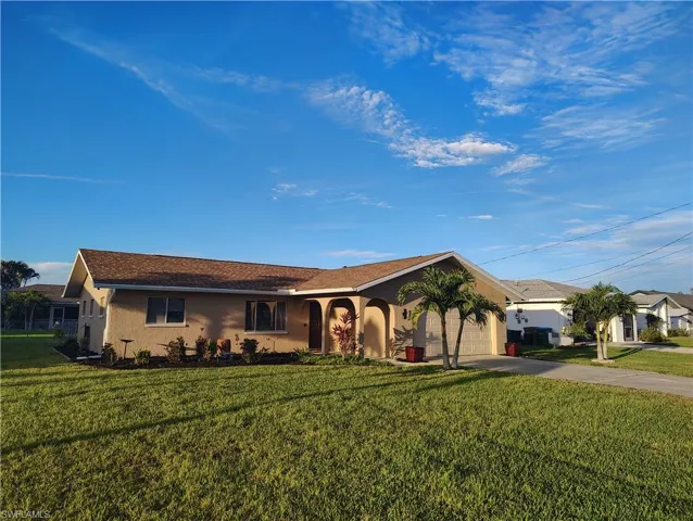 Ranch-style home with a front yard, concrete driveway, an attached garage, and stucco siding