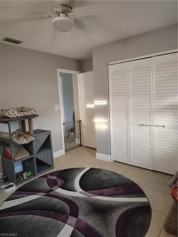 Living area featuring light tile patterned floors, visible vents, and baseboards