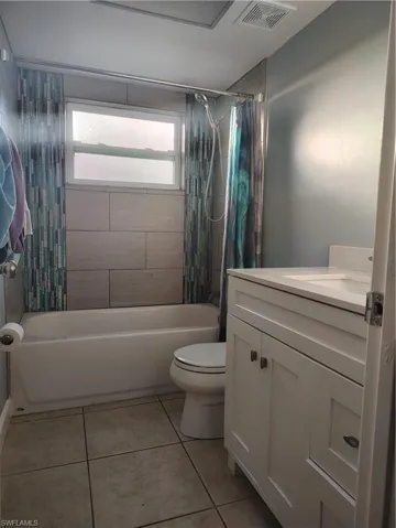 Bathroom with tile patterned flooring, toilet, shower / tub combo, vanity, and visible vents