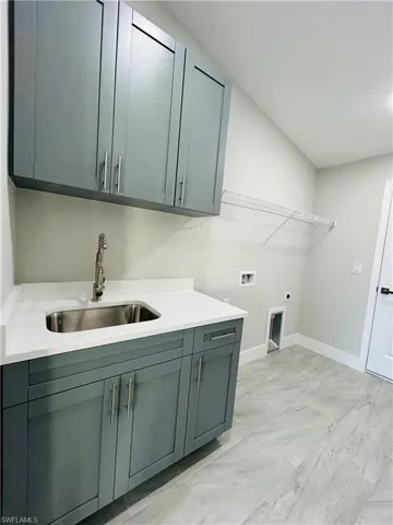 Laundry room with hookup for an electric dryer, sink, hookup for a washing machine, and cabinets