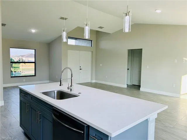 Kitchen with lofted ceiling, black dishwasher, a kitchen island with sink, and decorative light fixtures