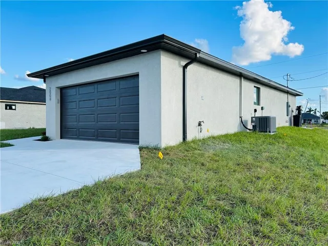 View of property exterior featuring a yard, a garage, and cooling unit