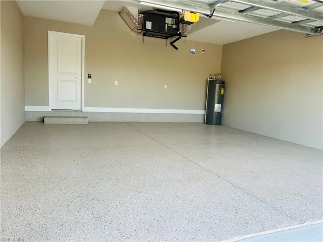 Garage featuring a garage door opener and electric water heater. Epoxy flooring.