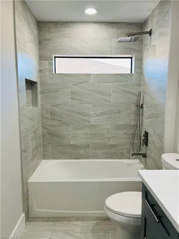 Full bathroom featuring vanity, toilet, and tiled shower / bath combo