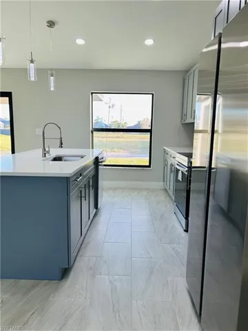 Kitchen with gray cabinets, sink, hanging light fixtures, and stainless steel appliances