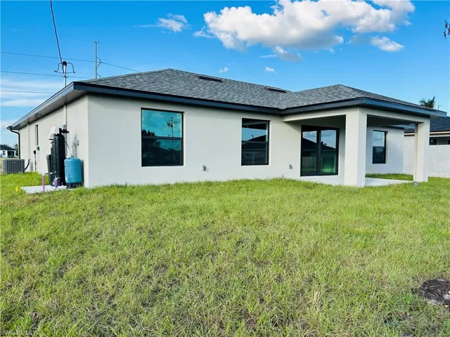 Back of house with cooling unit and a yard