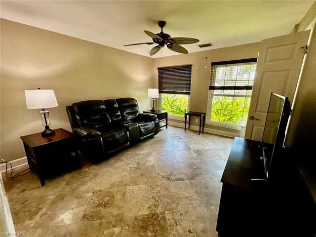 Spacious room featuring tile flooring, neutral wall tones, and two windows with blinds
