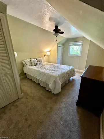 Carpeted room featuring a sloped ceiling, ceiling fan, and a window with blinds