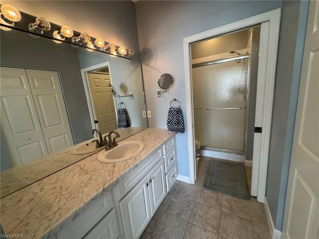 Bathroom with vanity, an enclosed shower, tile patterned floors, and toilet