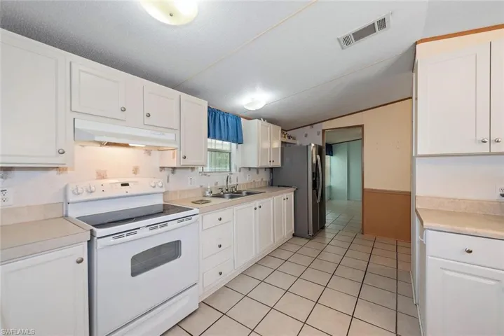 Kitchen featuring white electric range oven, white cabinetry, and under cabinet range hood