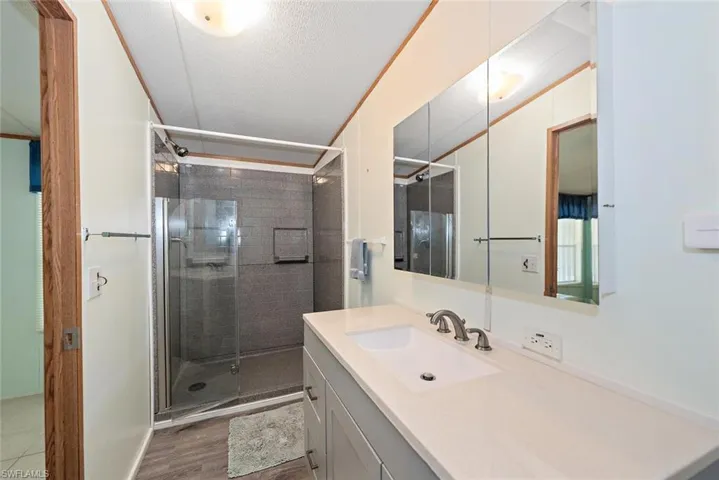 Bathroom featuring vanity, a stall shower, wood finished floors, and a textured ceiling