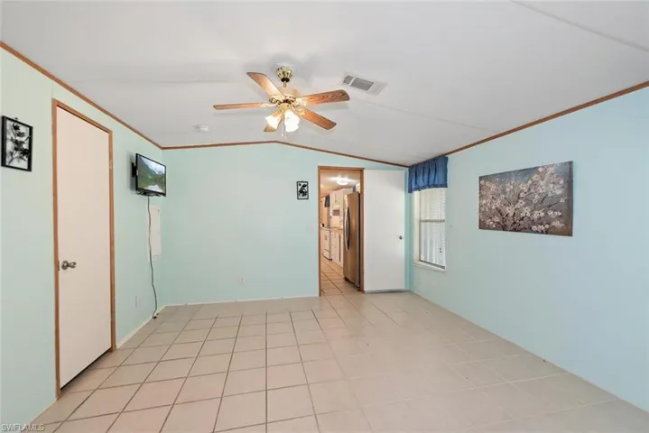 Spare room with vaulted ceiling, a ceiling fan, and crown molding