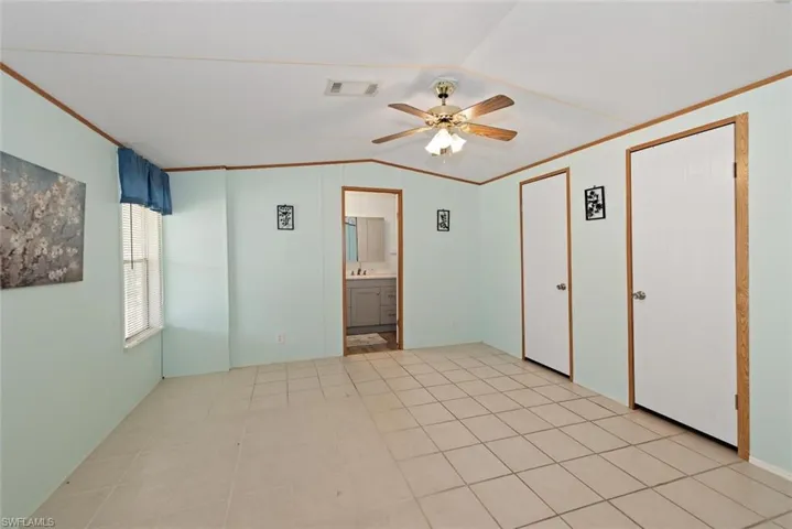 Unfurnished room featuring lofted ceiling, ceiling fan, and ornamental molding
