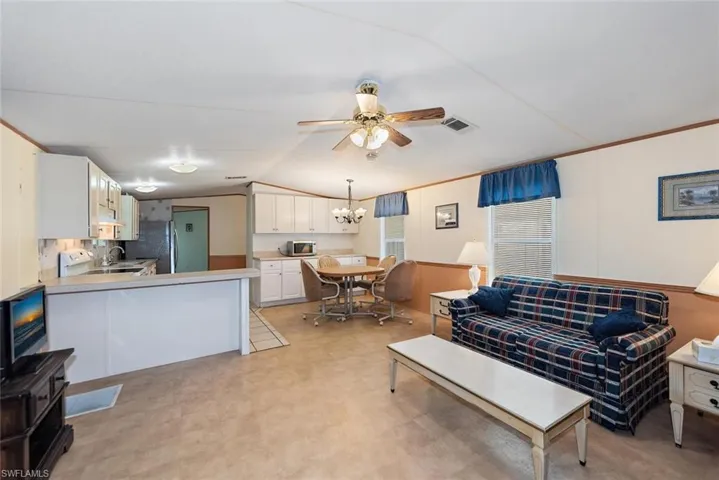 Living room with a chandelier, a ceiling fan, lofted ceiling, and light floors
