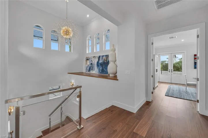 Entryway featuring ornamental molding, dark wood-type flooring, a notable chandelier, and french doors