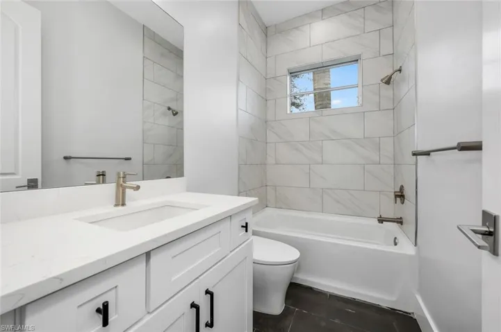 Full bathroom featuring vanity, tiled shower / bath combo, toilet, and tile patterned floors