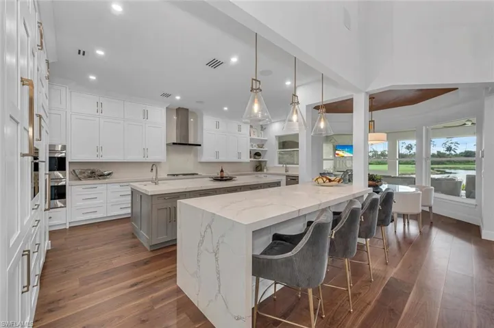 Kitchen with wall chimney exhaust hood, white cabinets, a kitchen island with sink, and dark hardwood / wood-style flooring