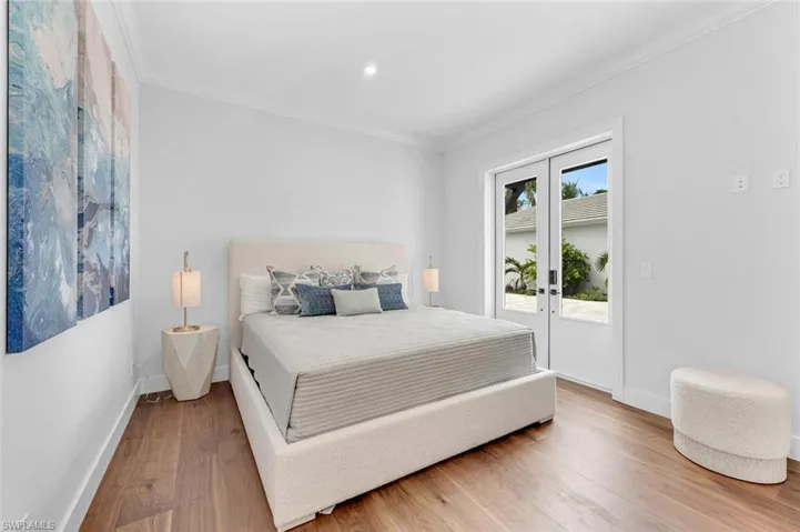Bedroom featuring french doors, wood-type flooring, ornamental molding, and access to exterior