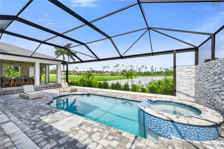 View of pool featuring an in ground hot tub, a water view, glass enclosure, and ceiling fan