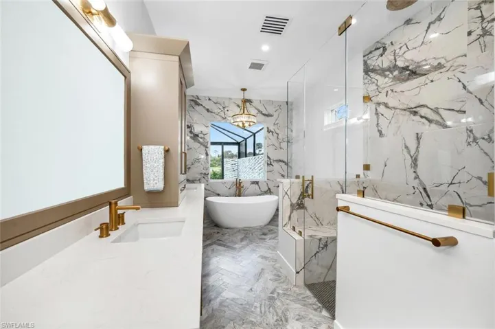 Bathroom featuring vanity, a chandelier, plus walk in shower, and tile walls
