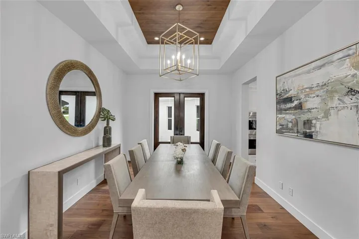 Dining room featuring french doors, wood ceiling, dark wood-type flooring, a tray ceiling, and an inviting chandelier
