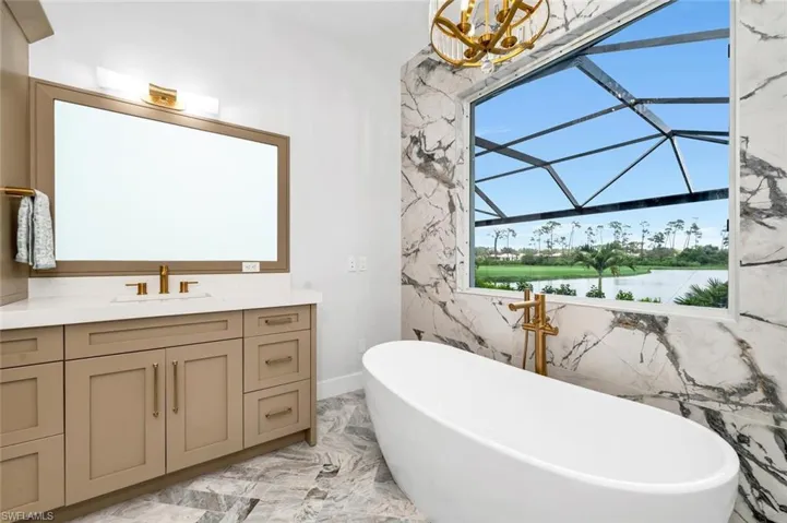 Bathroom with vanity, a water view, a bath, and a wealth of natural light