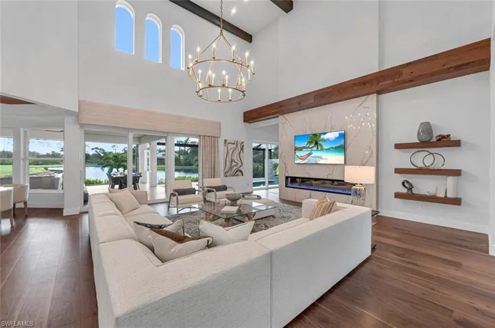 Living room featuring dark hardwood / wood-style floors, beam ceiling, an inviting chandelier, a fireplace, and high vaulted ceiling