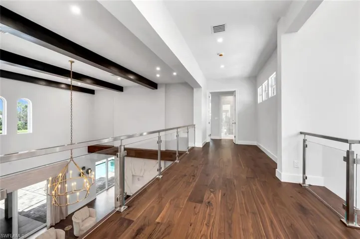 Corridor with dark wood-type flooring, beam ceiling, and a notable chandelier