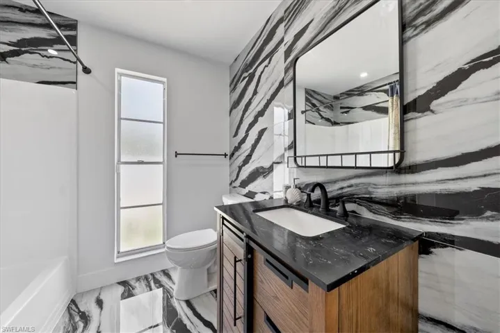 Bathroom featuring vanity, tub / shower combination, and light marble finish floors
