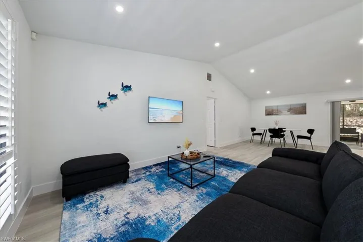 Living room featuring light wood-style floors, recessed lighting, and lofted ceiling