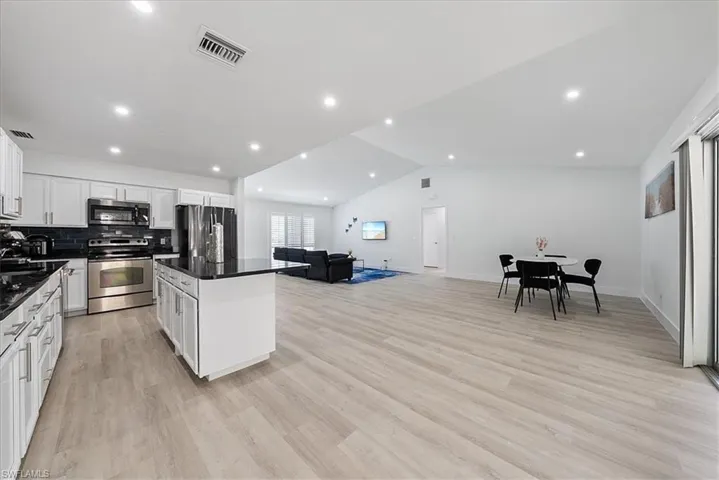 Kitchen with open floor plan, recessed lighting, appliances with stainless steel finishes, vaulted ceiling, and a center island