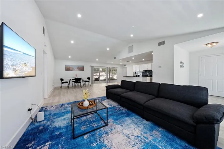 Living room featuring vaulted ceiling, recessed lighting, and wood finished floors