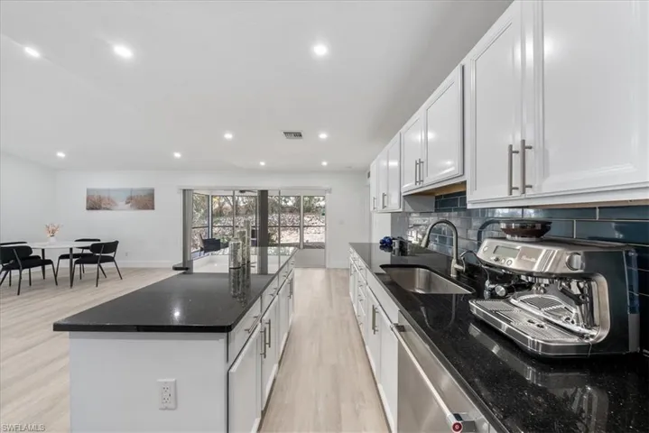 Kitchen featuring dark stone counters, light wood-style flooring, white cabinetry, decorative backsplash, and recessed lighting