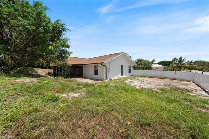 Rear view of property with a fenced backyard, stucco siding, and a sunroom